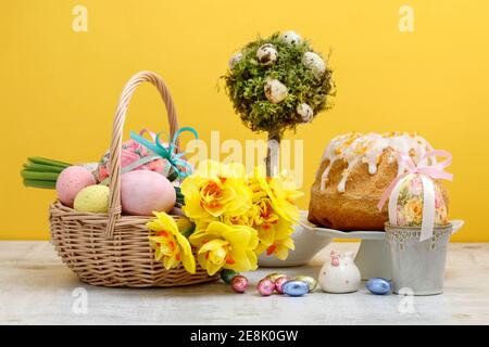 Weidenkorb mit Ostereiern und Blumenstrauß aus Narzissen. Festliche Einrichtung Stockfoto