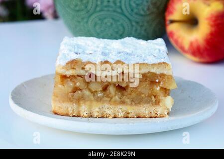 Portion Apfelkuchen und frische Äpfel im Hintergrund. Party-Dessert Stockfoto