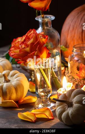 Herbsthochzeit Dekoration mit Kürbissen, Orangenrosen und Kerzen. Partydekor Stockfoto