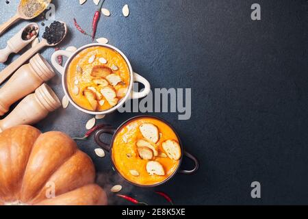Kürbiscremesuppe mit Croutons auf einem schwarzen Tisch mit Gewürze Stockfoto