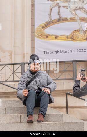 Junge asiatische Mann hat Foto gemacht, während sitzen auf Stein Steps in NYC auf Steps of New York The Metropolitan Museum of Art Stockfoto