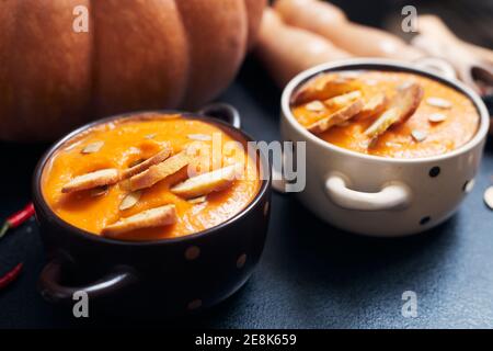 Kürbiscremesuppe mit Croutons auf einem schwarzen Tisch mit Gewürze Stockfoto