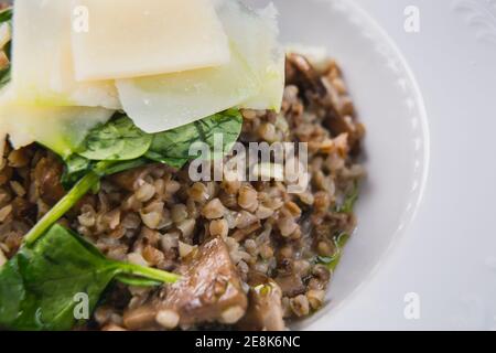 Nahaufnahme frisches Buchweizenrisotto mit Pilzen auf weißem Teller. Köstliche kulinarische vegane Speisen. Vegetarisches Konzept. Stockfoto