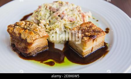 Schweinemedaillons mit Kartoffelpüree und Salat auf weißem Teller, für Restaurantmenü, Nahaufnahme Stockfoto