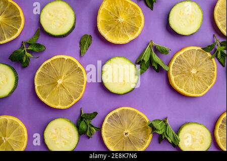 Zitronen- und Gurkenscheiben auf violettem Hintergrund Stockfoto