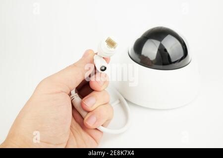 Person hält Stecker für die Kommunikation Sicherheit ip-Kamera. lan und Netzstecker aus der Nähe Stockfoto