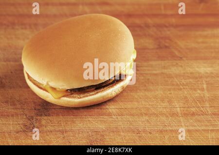 Schlanker Cheeseburger auf Holzbrett-Textur mit Kopierfläche. Leckerer Snack. Fast-Food-Konzept Stockfoto