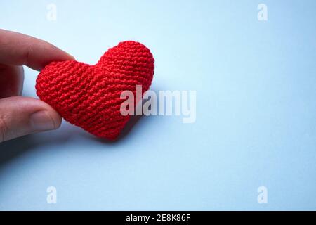 Rotes Herz aus Wolle auf hellblauem Hintergrund. Kopierraum. Romantik und valentinstag-Konzept Stockfoto