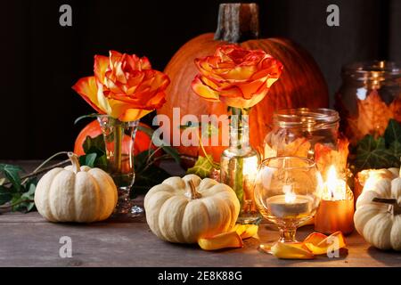 Herbsthochzeit Dekoration mit Kürbissen, Orangenrosen und Kerzen. Partydekor Stockfoto