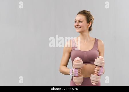 Arbeiten mit Hanteln junge Mädchen in engen rosa Outfit. Schöne Fitness-Mädchen Training Beine und Gewichte heben. Mädchen, Sport in einem Loft Stockfoto