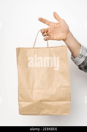 Mann Hand in Plaid Hemd verdreht Ärmel Hand hält braune Papiertasche isoliert auf weißem Hintergrund. Lieferkonzept. Papiertüte für Essen zum Mitnehmen Stockfoto