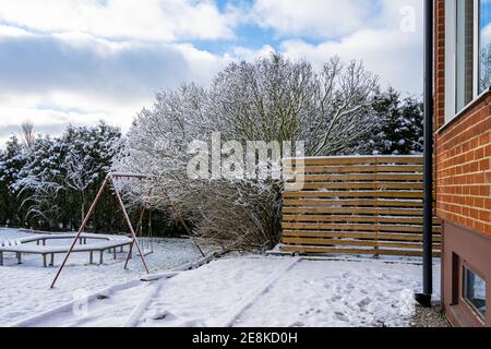 Winterbild eines Baumes und eines Holzzauns im Garten. Bild aus dem Landkreis Scania, Schweden Stockfoto