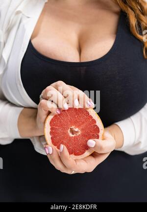 Body positive Mädchen hält einen Schnitt Hälfte einer frischen Grapefruit in den Händen stehen auf der modernen Küche zu Hause mit langen blonden Haaren. Diät und Stockfoto