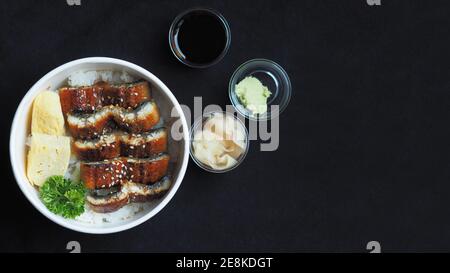 Draufsicht und Fokus auf Unadon oder unagi Donburi oder Aal Schüssel ist ein Gericht mit Ursprung in Japan auf schwarzem Hintergrund. Stockfoto