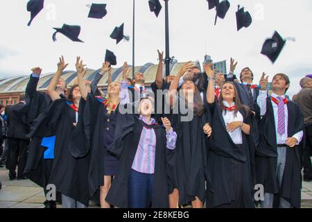 Kürzlich graduierte Studenten werfen ihre Mörtel Board Hüte In der Luft, um ihre Grad zu feiern Stockfoto