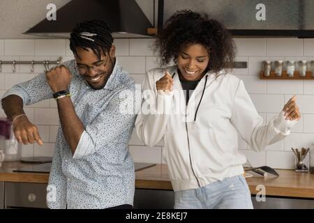 Aktives junges schwarzes Familienpaar genießen Tänze in der heimischen Küche Stockfoto