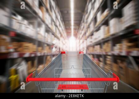 Ansicht der ersten Person oder Rückansicht des Supermarket-Gangs mit leerem roten Einkaufswagen mit verschwommenem Supermarkthintergrund. Stockfoto