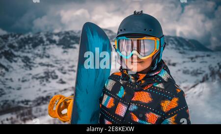 Nahaufnahme Porträt von Happy Active Girl genießen schöne Winter Skigebiet. Hübsche Frau trägt Schutzhelm und Maske, halten Snowboard. Stockfoto