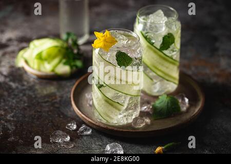 Gurke in ein Glas mit Eis eingegossen Detox-Wasser mit Minze. Hausgemachte Limonade mit Geschmack auf dunklem Hintergrund Stockfoto