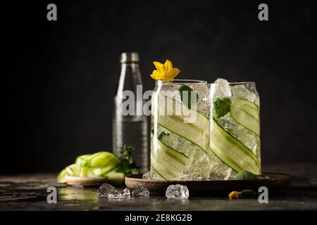 Gurke in ein Glas mit Eis eingegossen Detox-Wasser mit Minze. Hausgemachte Limonade mit Geschmack auf dunklem Hintergrund Stockfoto