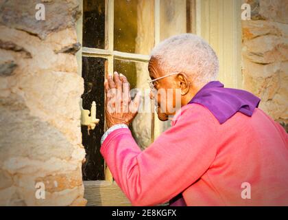 90-jährige ältere Frau, die durch das Fenster einer historischen Kirche blickt, die sie vor vielen Jahren in Waterford, Virginia, besuchte. Stockfoto
