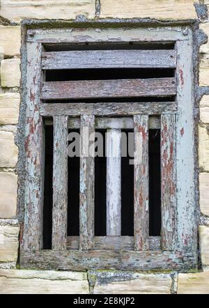 Alte Holzrahmen und versperrte Fenster mit abblätternder Farbe innen Eine steinerne Scheune Stockfoto