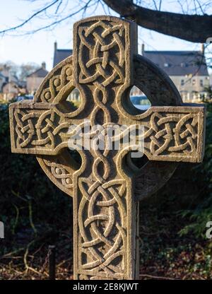 Sonnenbeschienene tief geschnitzte Grabmarke aus Stein mit keltischem Kreuz Design auf einem Friedhof in Yorkshire Stockfoto