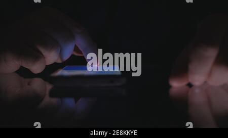 Night Shoot mit einem Geschäftsmann mit Handy-Kommunikation. Man Text auf einem Smartphone. Stockfoto