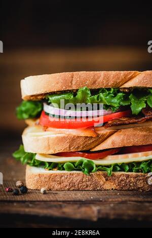 Großes Club Sandwich mit Speck, truthahn, Käse, Salat und Tomaten. Nahaufnahme Stockfoto