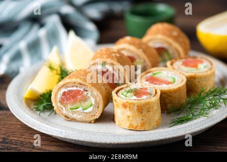 Crepe Brötchen mit Lachs und Frischkäse auf einem Teller. Party Essen, Feiertagstisch Vorspeise Stockfoto