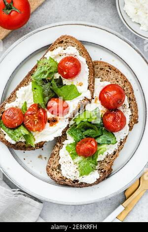 Geröstete Tomaten und Ricotta Roggen Bruschetta. Leckere gesunde Toast, italienische Küche Stockfoto