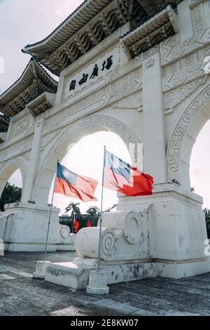 Nahansicht des Liberty Square Arch in Taipei mit der Flagge Taiwans, die im Wind winkt, und dem Licht, das von hinten durchscheint. Stockfoto