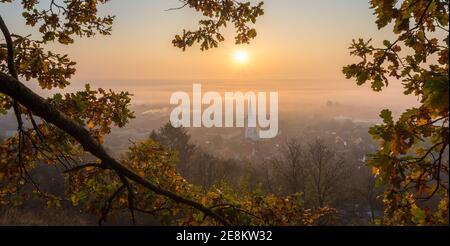 Landschaftlich schöner Panoramablick auf einen Sonnenaufgang über einem Dorf in Ein nebeliges Tal Stockfoto