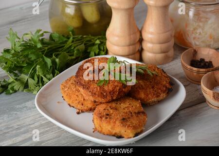 Saftig gebratene hausgemachte Hähnchenschnitzel. Mit Paniermehl überzogen, köstlich, in weißer Schale mit Kräutern. Auf altem Holzhintergrund, rustikaler Stil Stockfoto