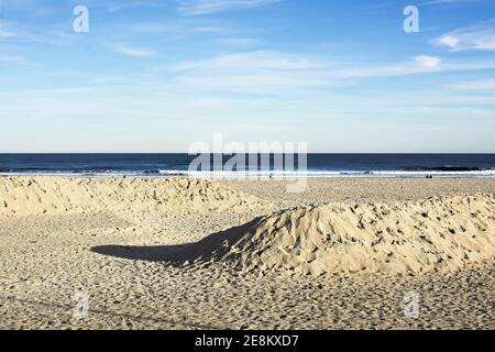 Hampton Beach State Park - Hampton, New Hampshire - an einem hellen Winterabend, wenn die Sonne untergeht, erheben sich zwei leere Sanddünen über dem Strand. Stockfoto