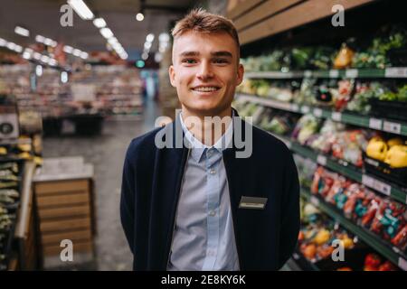 Nahaufnahme eines jungen männlichen Verkäufers. Mann in Uniform arbeitet im Supermarkt lächelt an der Kamera. Stockfoto