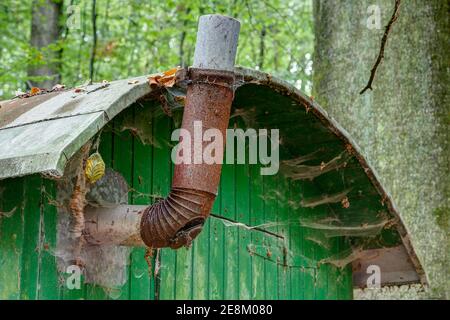 Alte rostige Metallstovepipe und Spinnweben unter dem Zinndach auf einem Wetterschutzkarawane für Waldarbeiter. Stockfoto