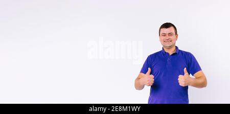 Banner, Langformat. Ein taubstummer Mann mit einem glücklichen Lächeln schaut auf die Kamera und zeigt wie. Daumen hoch auf weißem Hintergrund mit seitlichem Abstand. Stockfoto