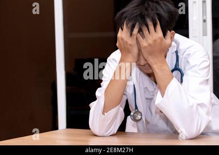 Ein Arzt legte seine Hand auf seinen Kopf, als er gestresst war. Überarbeiteter Arzt im Krankenhaus. Weil er zu hart arbeitet. Stockfoto
