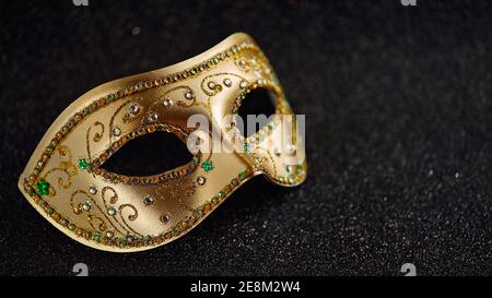 Festliche, bunte Mardi Gras oder Karnevalsmaske auf schwarzem Glitzer-Hintergrund. Venezianische Masken. Partyeinladung, Grußkarte, venezianische Karnevalsfeier cebr Stockfoto