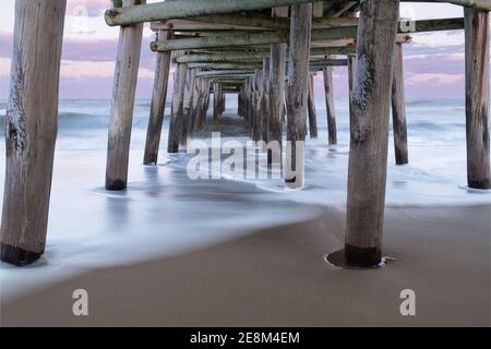 Der Sandbridge Fishing Pier in Virginia Beach bei Sonnenuntergang, mit langer Belichtung macht das Wasser seidig und verträumt Stockfoto