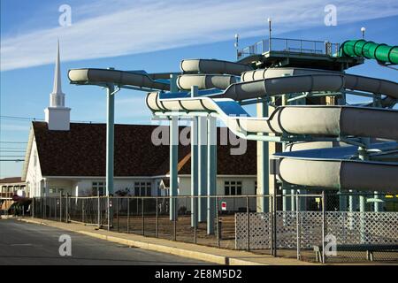 Hampton Beach - Hampton, New Hampshire - eine leere Wasserrutsche steigt und dreht sich vor einer Kirche und Kirchturm einen Block von der Promenade während der Sonne Stockfoto