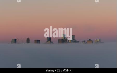 Stadt in den Wolken, Paradise City, City of Angels, Vancouver City Wolkenkratzer über dem Nebel mit der Morgensonne, die einen reflektierenden falschen Sonnenuntergang erzeugen Stockfoto