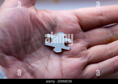 Konzept - Nahaufnahme einer Person, die das letzte Stück hält Des Puzzles in der Handfläche ihrer Hand Stockfoto