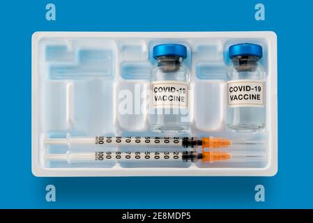 Coronavirus-COVID-19-Impfstoff. Fläschchen mit Spritzen in weißer Box auf blauem Hintergrund, Konzeptkomposition in Draufsicht, flach liegend Stockfoto