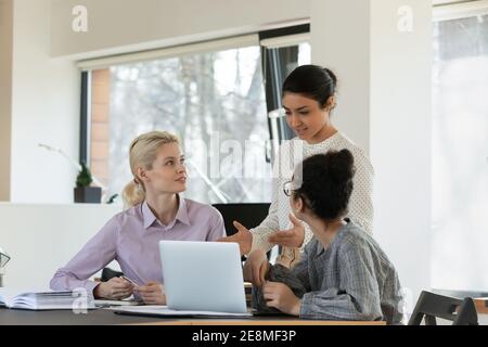 Selbstbewusste indische Teamleiterin, die Mitarbeiter am Arbeitsplatz unterweist Stockfoto