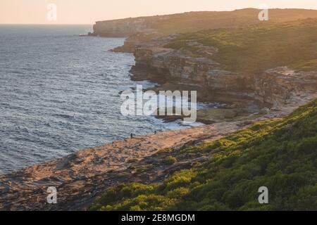 Felsige Küste und Heide am Meer im Royal National Park bei Sonnenuntergang in den östlichen Vororten von Sydney, NSW, Australien. Stockfoto