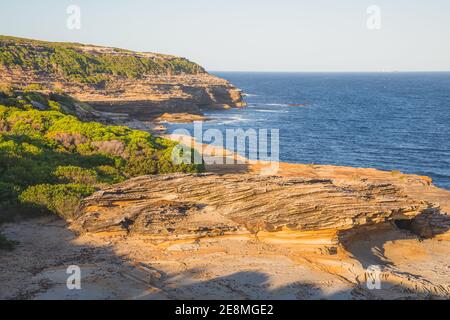 Felsige Küste und Heide im Royal National Park an einem sonnigen Sommertag in den östlichen Vororten von Sydney, NSW, Australien. Stockfoto