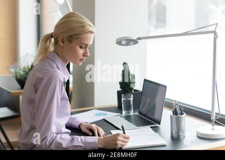 Fokussierte Millennial-Studentin, die sich das Webinar auf einem Laptop ansieht Stockfoto
