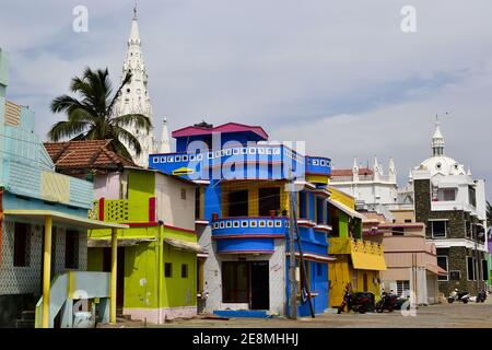 Kanyakumari, Tamil Nadu, Indien - Januar, 2017: Bunte Häuser von Fischern und ein Teil der alten Kolonialkirche am Meer in der Nähe des Meeres Stockfoto